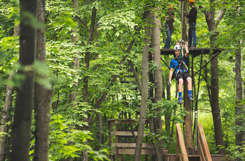 Boy zipliner flying through the air after jumping off platform