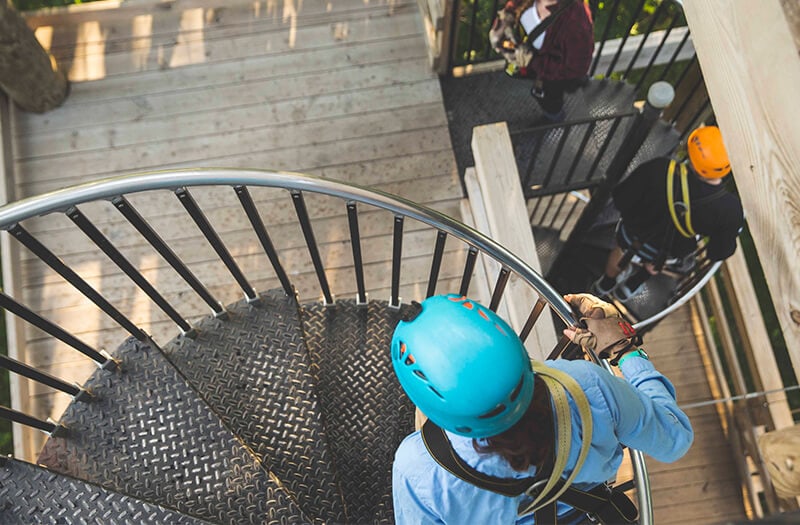 Man walks up spiral staircase as he prepares to zipline