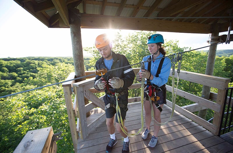 Man and women prepare to zipline through the air.