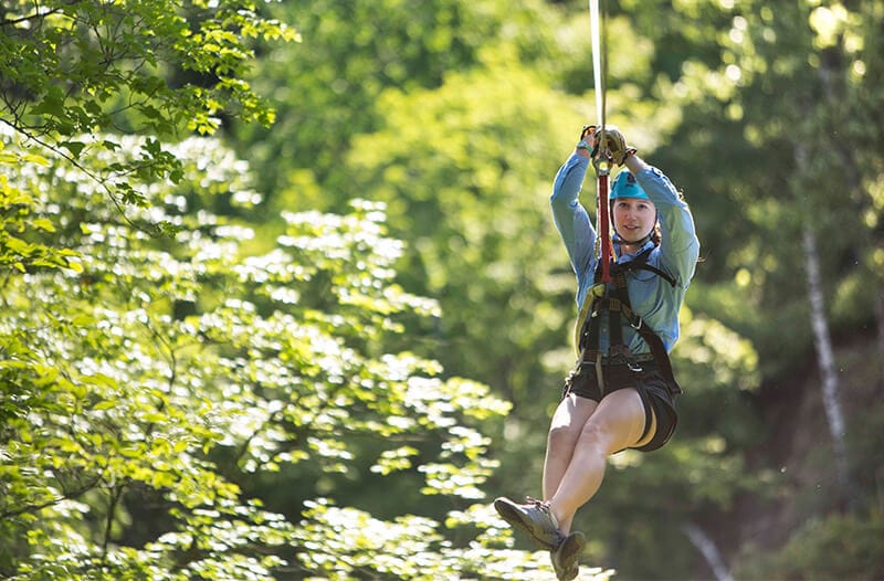 Girl zipliner flies through the trees on a zipline
