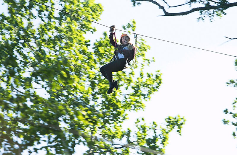 Girl zipliner looks down at the camera making a silly face