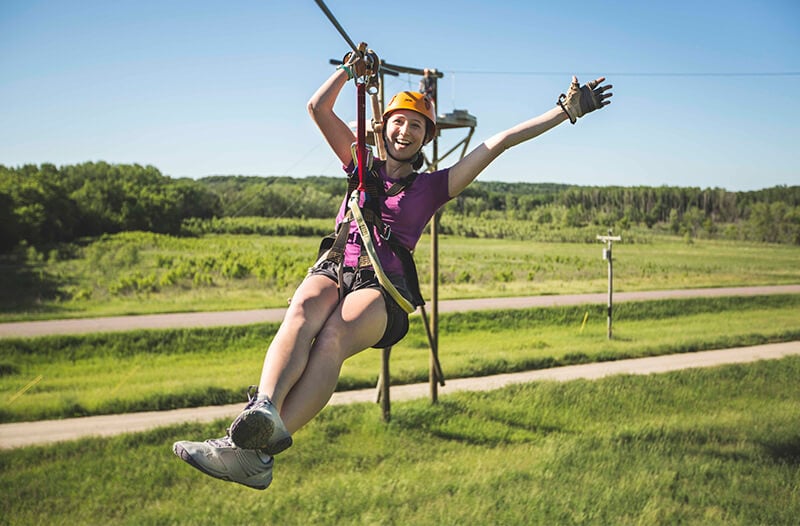 Happy zipliner flies over field