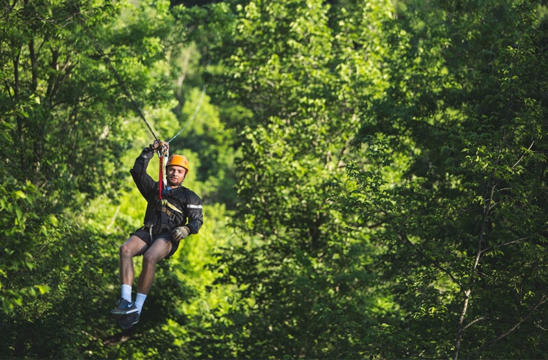 Man Zip lining through the trees