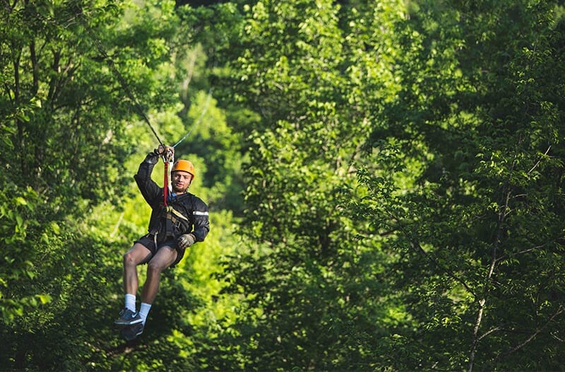 Man ziplines through a forest